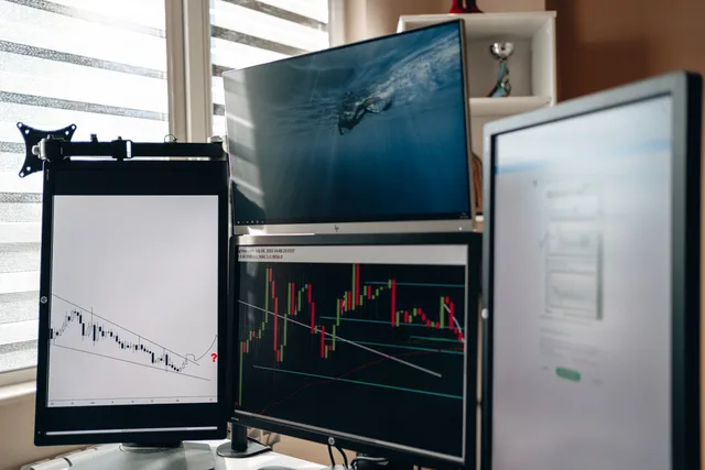 A home office setup featuring multiple monitors displaying trading charts and data analysis. Attribution reporting templates UK: examples for agencies