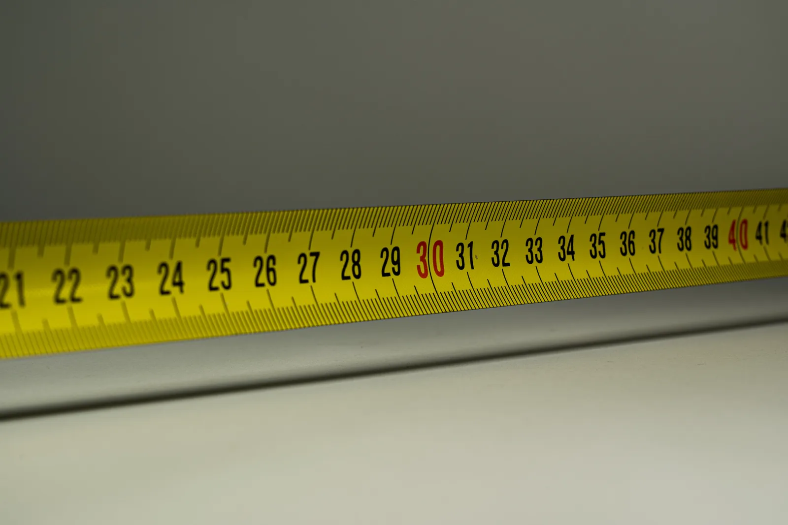 Close-up view of a yellow measuring tape with centimeter marks, emphasizing precision in measurement.