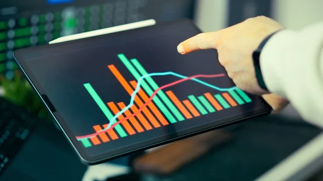 A person analyzing business data with colorful graphs on a tablet screen. A marketing attribution strategy framework for buyer decisions