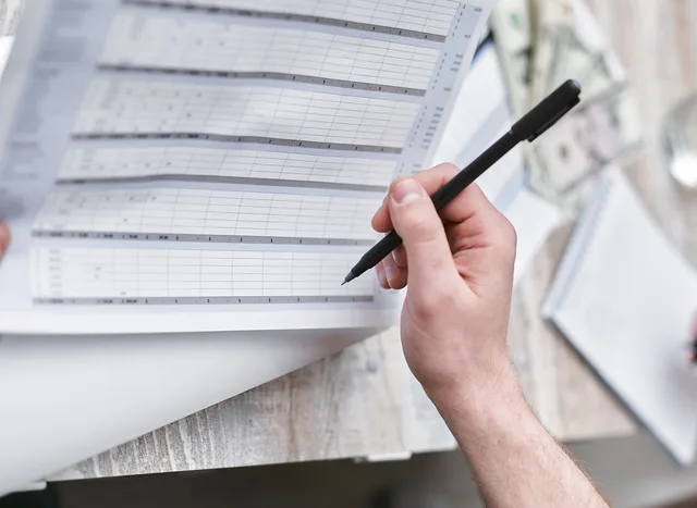 A close-up of a person holding a pen reviewing a financial document with cash visible, ideal for business themes. Five attribution mistakes to check before changing a plan