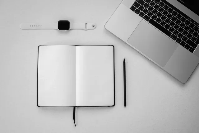 Top-down view of a minimalist workspace featuring a laptop, blank notebook, smartwatch, and pencil. Attribution supplier routes on one matrix, with the commercial unit kept blank