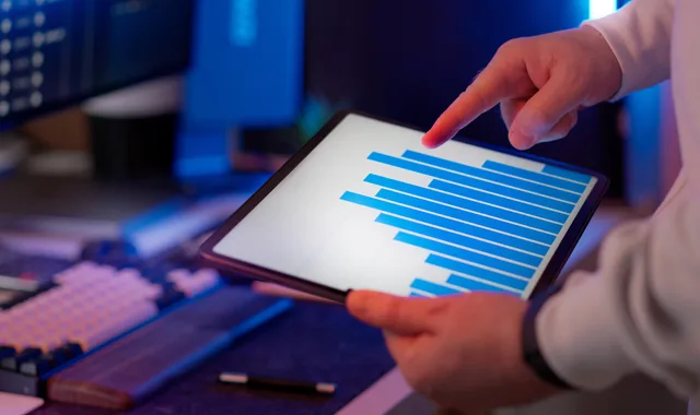 Business professional analyzing bar chart on tablet in office setting, highlighting data insights. Marketing attribution target audience for platform research
