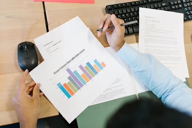 A business analyst reviews a colorful bar chart and documents at a desk, indicating data analysis. Matching attribution tools to jobs, and what each must show first